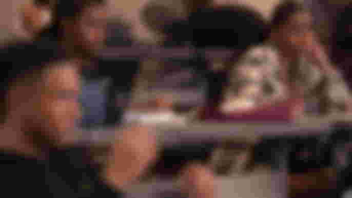 All American: Homecoming Season 1 Geffri Maya as Simone looking at Peyton Alex Smith as Damon in class