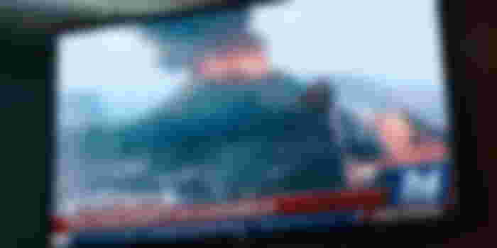 Superman on a television screen flying and using heat vision