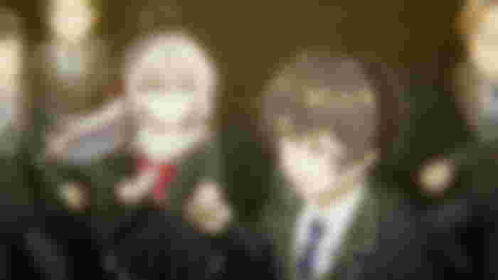 a boy and a girl are holding hands in front of a group of people .