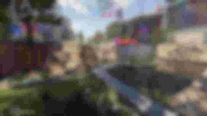 A player running through the Nudleplex plaza with an SMG in their hands, showing a small pond and rock walls nearby.