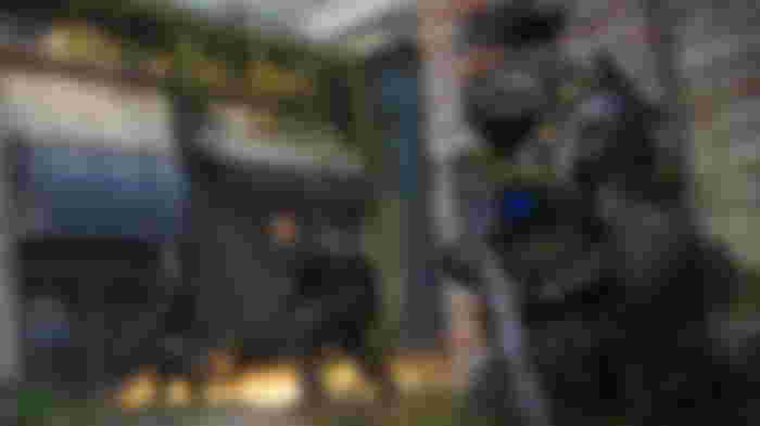 Warzone Captain Price crouching while holding sniper rifle with players in background