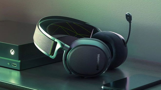 A black overear wireless headset with a mic laying propped up against a black Xbox.