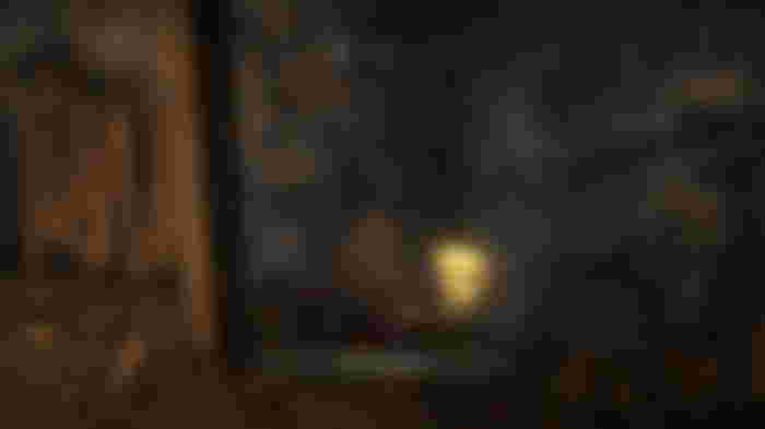 A Prisoner standing next to a golden glowing ore. They are holding a torch. Text reads: 'Acquire Materials'