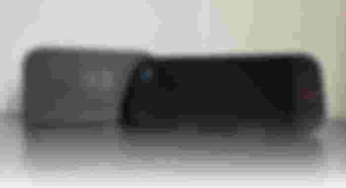 A black Switch 2 leaning up against its black charging dock.