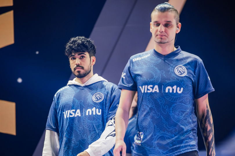 two men in blue jerseys are standing next to each other on a stage .