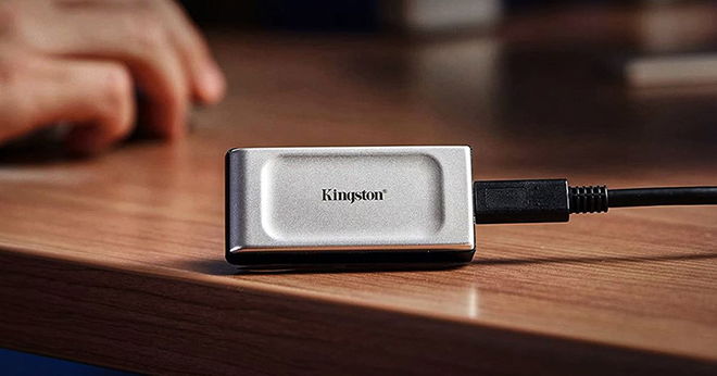 A silver and black external SSD sat on a brown wood table.