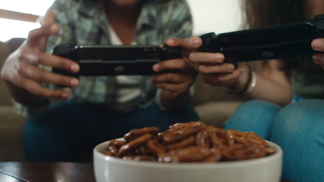 Players using the Backbone One as a controller in front of a bowl of pretzels.