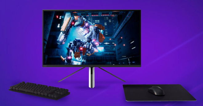 A white and black monitor with a silver and orange robot on the display next to a keyboard, mouse, and mouse mat in front of a purple background.