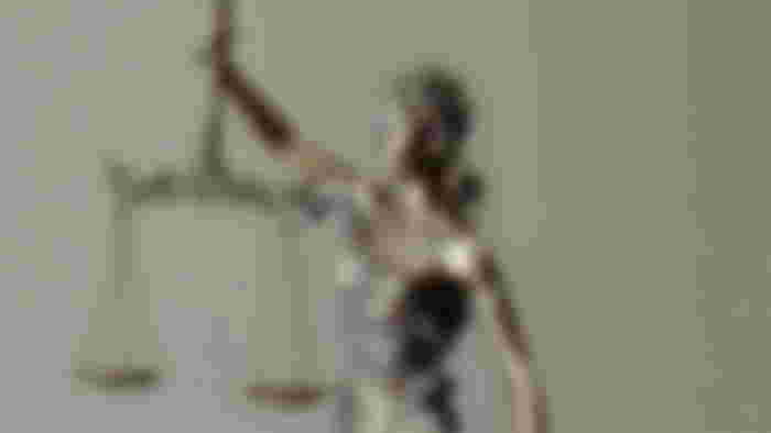 A gold statue of a woman holding a perfectly balanced scale.