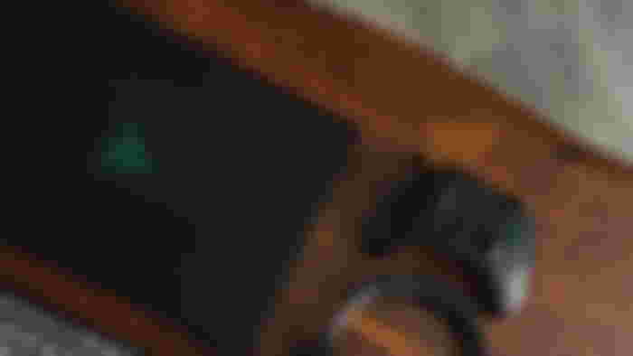 Black Razer gaming laptop on a wood table next to a black Xbox controller.