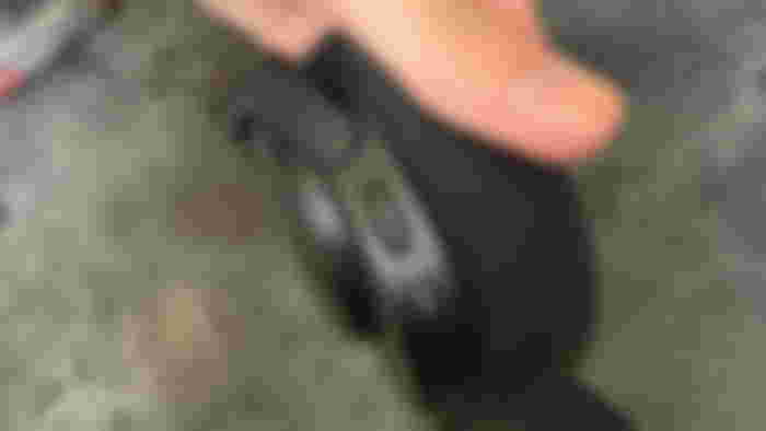 Someone holding the SteelSeries Arctis Nova 5 headphones' left earcup showcasing the volume wheel and the mute button