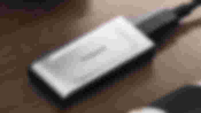 A silver and black external SSD placed on a brown wood surface.