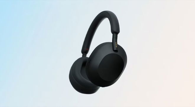 WH-1000XM5 noise-cancelling headphones in black in front of a light blue and cream gradient background.
