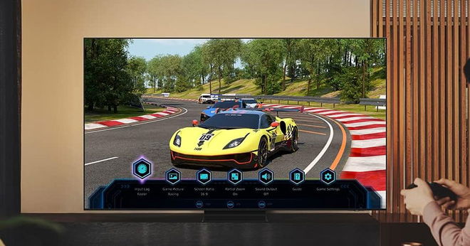 A black near-frameless TV with a racing video game on the display, with a yellow car with white trim on a track.
