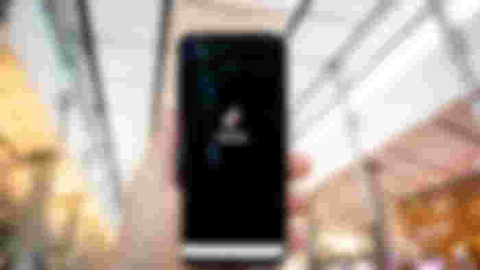 Hand of man holding mobile phone opening Tik Tok application, in shopping mall.