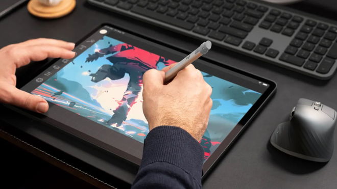 Someone using a silver stylus to draw on a black tablet.