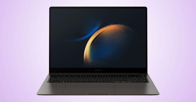 A dark grey and black thin laptop with a dark blue and orange circular pattern on the display in front of a light purple gradient background.