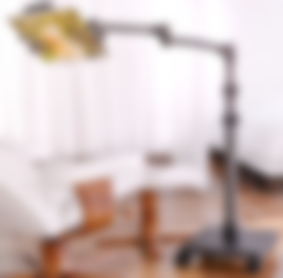 An extendable black stand with a tablet attached over a bed.