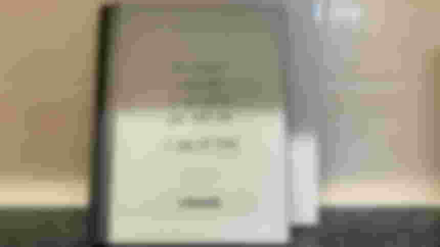 The reMarkable 2 device standing in front of its box and in front of a tiled wall.
