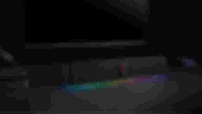 A black soundbar featuring RGB lighting in front of a monitor.