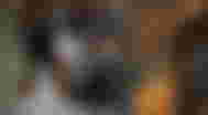 A black set of over-ear headphones with a white boarder in front of a blurry images of someone wearing a identical cream-white set.