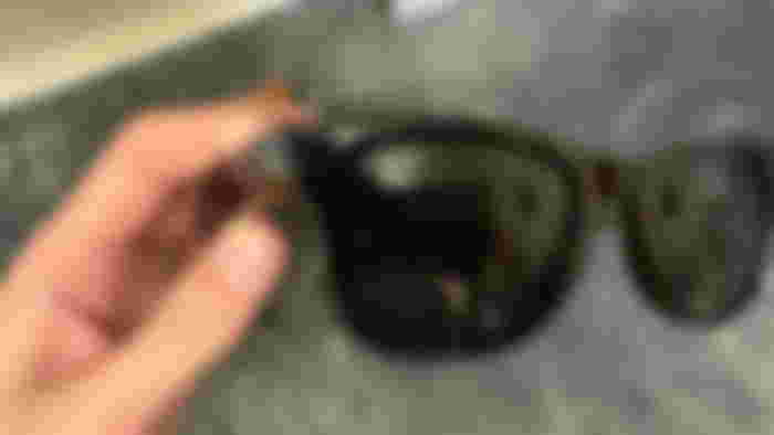 Myself holding a pair of Ray-Ban Meta sunglasses with a focus on the camera