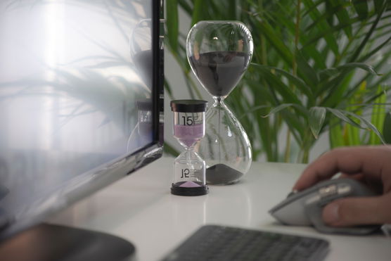best-time-management-apps | A person working on a computer with a sand clock on his desktop.