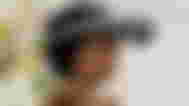 A woman with dark curly hair wearing the Sony MR headset with the top flipped up