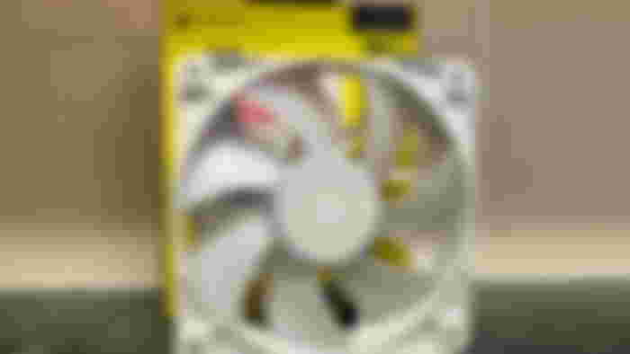 A white Corsair RX120 Fan in front of its box on a marble counter top