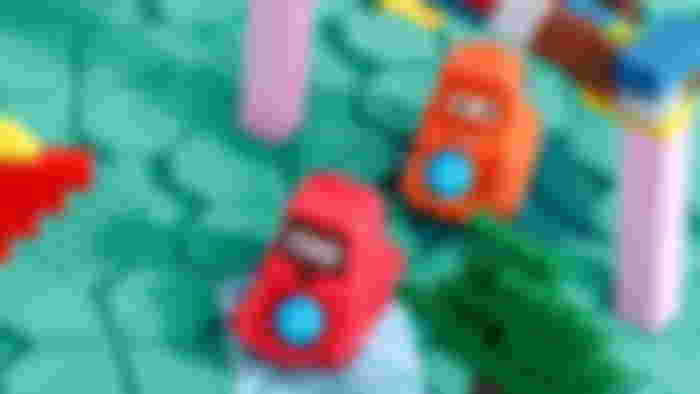 A red and a orange dinner kids toy on a building block green surface.