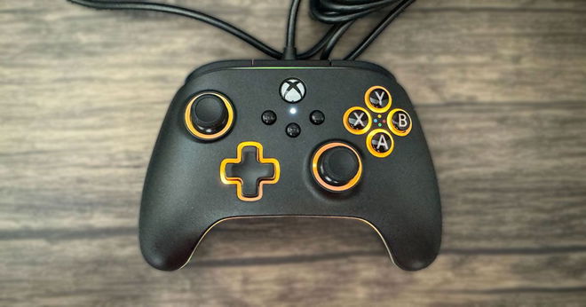 A black Xbox-branded wired controller featuring orange lights around the buttons.