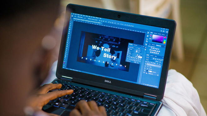 Someone editing a piece on work on Photoshop on a black Dell laptop.