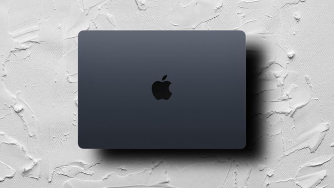 A dark gray Macbook Air in front of a cream textured background.