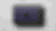 A dark gray Macbook Air in front of a cream textured background.