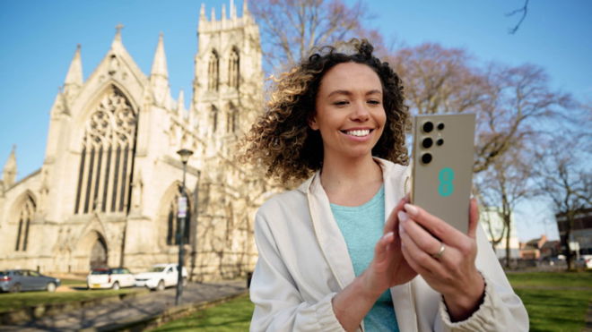 Women using a Samsung phone with EE branding outside a church.