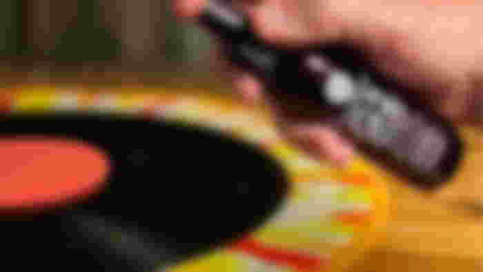 GrooveWasher-branded black bottle spraying a black vinyl record.