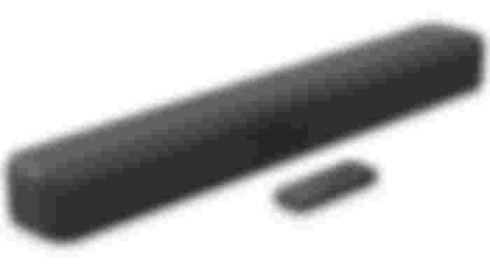 A rectangular black soundbar with a remote in front of it.