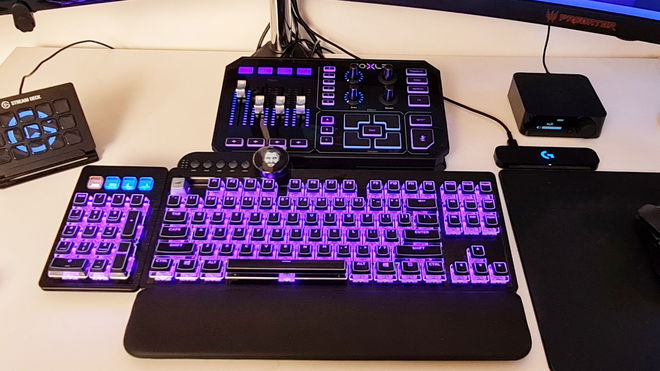 A GoXLR audio mixer sits above a gaming keyboard with the same purple and blue lighting theme