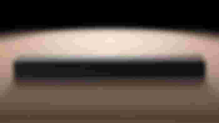 A long black LG soundbar on top of a light wood surface.