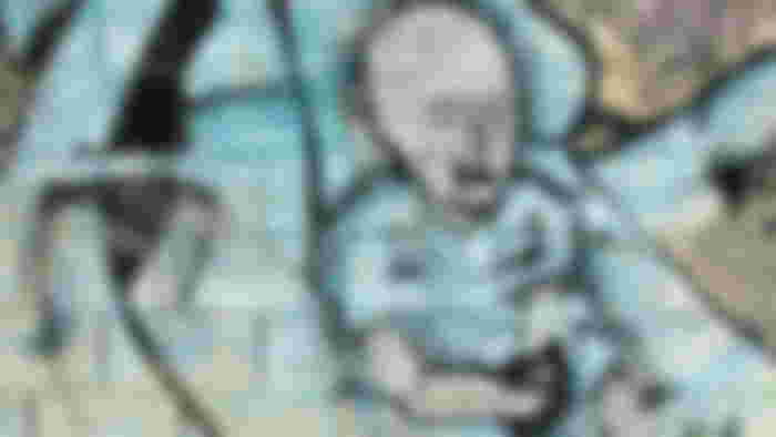 A wall mural of a person that has their eyes closed and a cross over their mouth