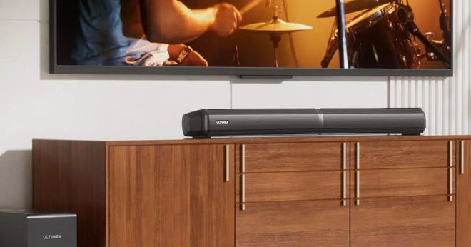 A long black subwoofer on a brown stand sat below a wall-mounted TV.