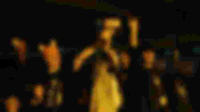 A group of friends holding the Nintendo DS up high as if it is some form of messiah