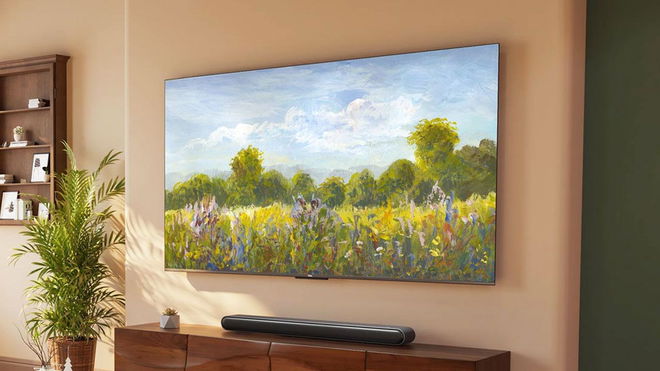 A frameless TV with a painted field and sky setting on the display mounted to a tan wall above a black soundbar and brown cabinet.
