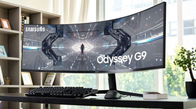 Image of an ultrawide, black Samsung monitor featuring a Sci-Fi scene on the display sat at a desk.