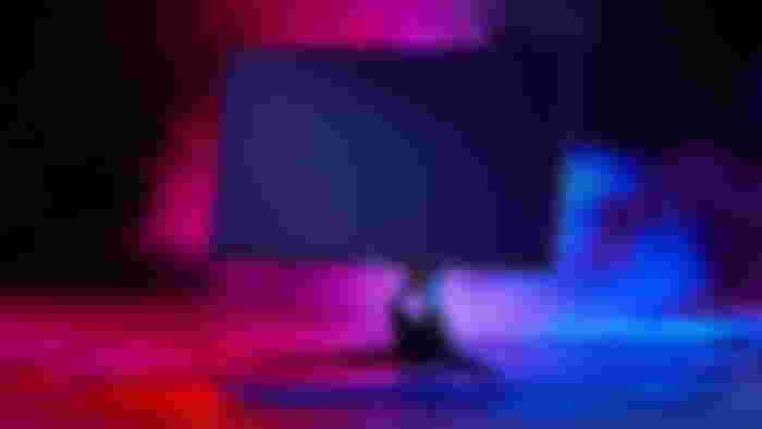 Image of a black gaming monitor surrounded by red and blue lighting and smoke.