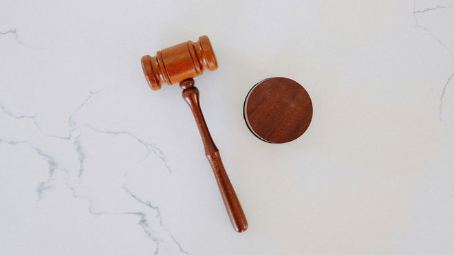 A wooden gavel on a white marble backdrop.