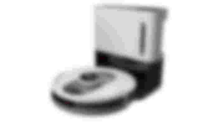 A circular white and black robot vacuum connected to its dock