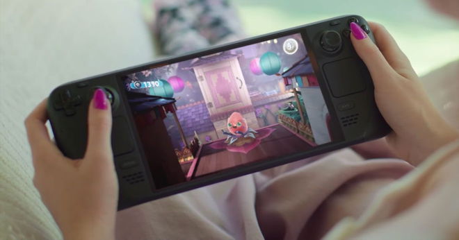 Someone with pink painted nails playing a black handheld gaming device with a bright OLED screen.