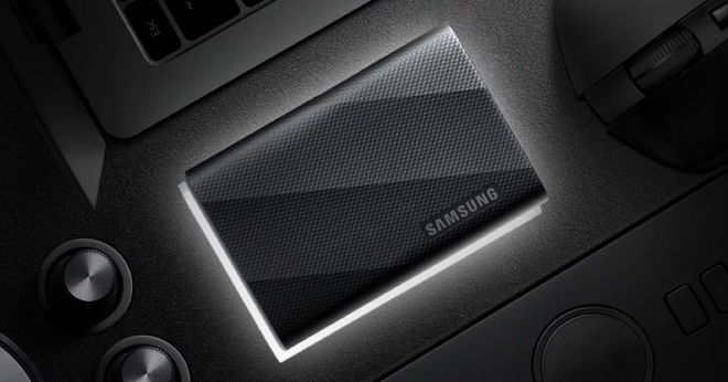 A black rectangular SSD placed on a black desk with a white light behind it.