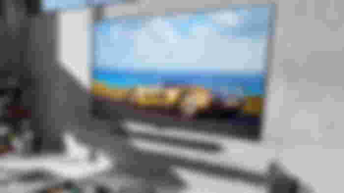 LG G4 OLED TV showing a yellow supercar on a grey tiled wall